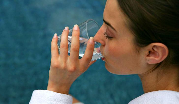 Девушка пьет воду с содой из стакана